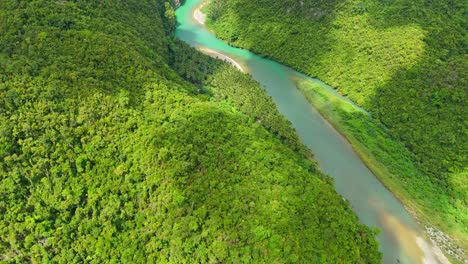 An-aerial-drone-shot-of-Daywan-River,-Surigao-Del-Norte---Philippines,-with-stunning-turquoise-water,-sitting-in-a-valley-of-beautiful-dense-lush-jungle