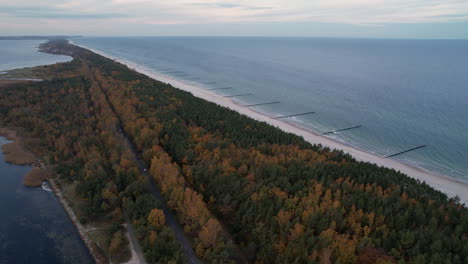 Road-nestled-between-a-colorful-autumn-forest-and-a-serene-coastline-at-dusk---Hel-Peninsula