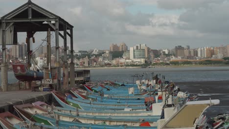 Barcos-De-Pesca-Atracados-En-Un-Puerto-De-Taipei,-El-Horizonte-De-La-Ciudad-En-Segundo-Plano.