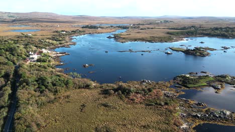Aerial-view-over-the-enchanting-connemara-lakes-in-ireland-with-a-view-of-the-reflecting-blue-river-with-autumnal-vegetation-and-mountains-in-the-background