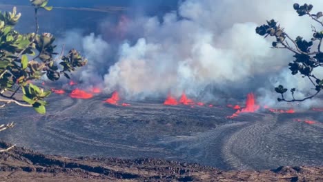 Cinematic-long-lens-panning-shot-of-lava-fountains-erupting-from-Kilauea-while-framed-by-tree-branches-on-the-first-day-of-activity-in-September-2023-on-the-Big-Island-of-Hawai'i