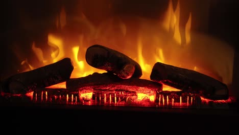 hand-held-shot-of-a-electronic-fireplace-warming-up-with-wooden-logs-on-fire