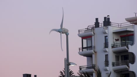 Static-shot-of-Wind-turbine-Eco-friendly-housing-in-Cascais-during-sunset