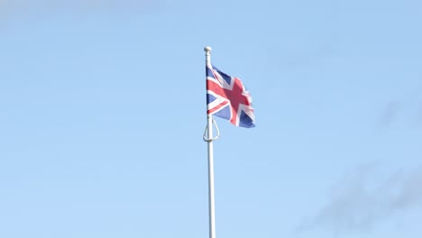 hand-held-shot-of-a-union-jack-flag-flying-in-thew-wind-on-a-pole