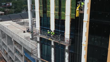 Drone-shot-showing-worker-installing-windows-on-new-tower-building-at-construction-site