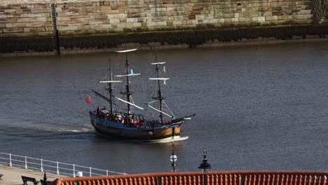 hand-held-tracking-shot-of-a-pirate-ship-sailing-into-Whitby-Harbour