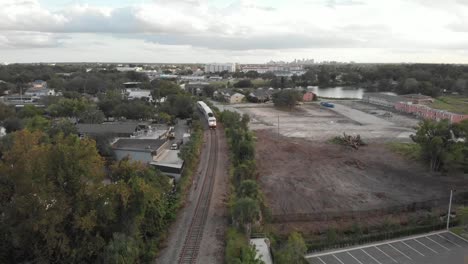 Industrial-area-with-train-passing-by-on-tracks-parking-lot-buildings-storage-unit-nearby