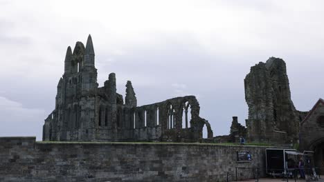 Panning-shot-of-tourists-walking-alongside-the-ticket-office-at-Whitby-Abbey