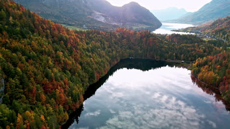 Aerial-view-of-mirroring-water-and-vibrant-autumn-trees-at-lake-Toplitz-in-Austria