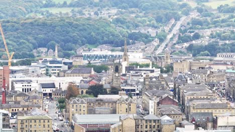Historic-rock-clock-tower-and-church-steeple-between-industrial-zone-of-Huddersfield