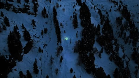 Drone-captures-a-hiker-navigating-through-a-vast,-snowy-mountainscape,-revealing-the-grandeur-of-nature