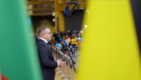 Finish-Prime-Minister-Petteri-Orpo-explaining-himself-at-the-European-Council-summit-in-Brussels,-Belgium---Cinematic-flag-shot