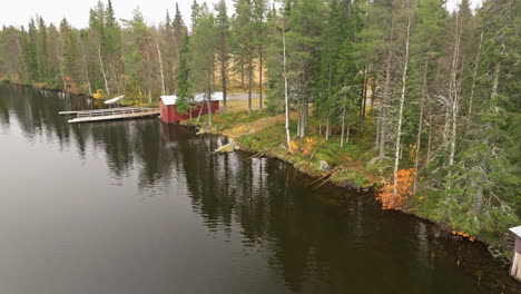 Herbstwald-Und-Rote-Fischerhäuser-Am-Ruhigen-Seeufer-Während-Bewölktem-Morgen-In-Schweden