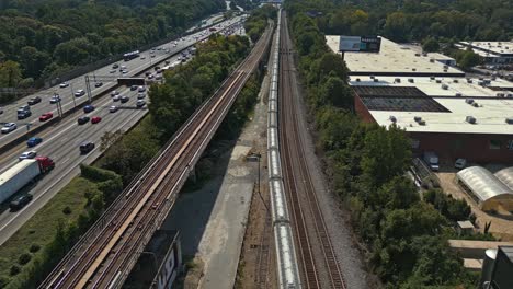 Aerial-top-down-shot-of-busy-highway-with-train-during-sunny-day-in-Suburb-area-of-Atlanta