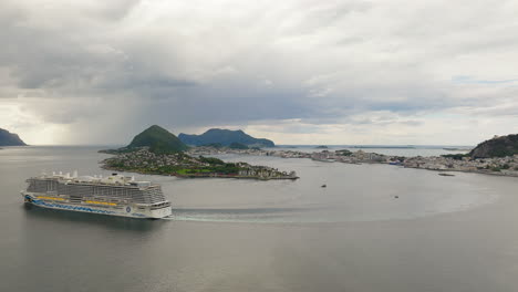 High-angle-side-view-of-cruise-ship-departing-Alesund-on-Geirangerfjord,-Norway