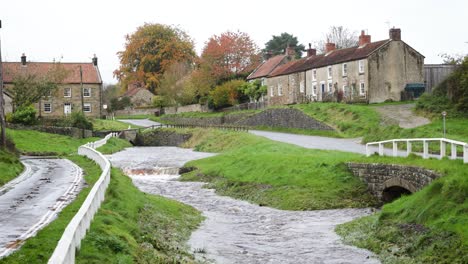 Hutton-Beck-running-very-high-through-Hutton-le-Hole,-after-a-rainy-spell-November-2023