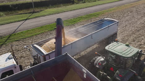Semi-Truck-Trailer-Being-Filled-With-Grain-Crop-Harvest-from-a-Grain-Cart,-Aerial