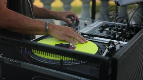 Close-up-of-Wedding-DJ-man-play-and-adjust-controller-with-yellow-vinyl