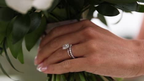 Close-up-of-brides-diamond-wedding-ring-while-hold-a-flower-bouquet-in-hand