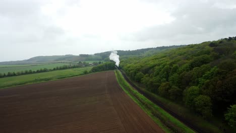 Drone-Footage-of-a-Steam-Train-and-carriages-approaching-with-clouds-of-steam-along-the-Poppy-in-North-Norfolk