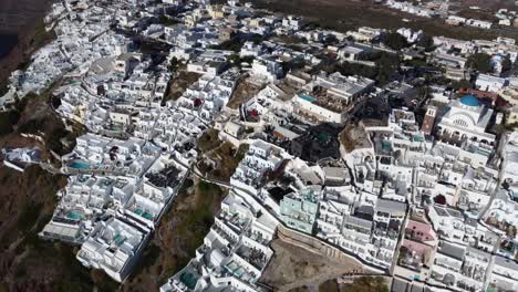 Oia-village-cliffside-houses-and-hotels-in-Santorini,-Greece,-Cinematic-aerial-view