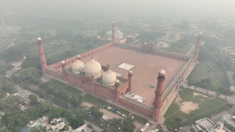 Toma-Aérea-De-La-Mezquita-Badshahi-En-Lahore,-Pakistán,-A-Través-Del-Aire-Brumoso
