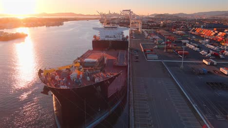 Large-cargo-ship,-the-USNS-John-Glenn,-docked-in-the-Port-of-Oakland,-aerial-establishing-view
