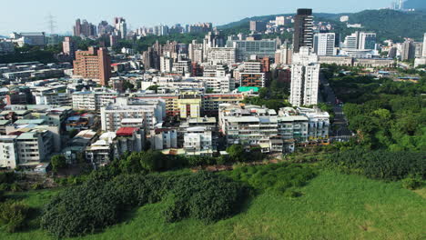 Toma-Aérea-De-Edificios-De-Viviendas-Rodeados-Por-El-Parque-Natural-Guandu,-Taipei