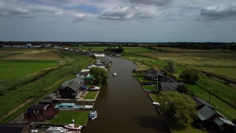 Luftdrohne-4K-Aufnahmen-Eines-Bootes,-Das-Entlang-Des-Flussgeländes-An-Einigen-Häusern-Am-Flussufer-Vorbeifährt,-Norfolk