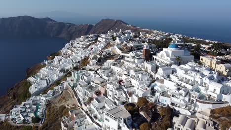 Oia-village-cliffside-houses-and-hotels-in-Santorini,-Greece,-Cinematic-aerial-view