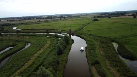 Aerial-Drone-4k-Footage-of-a-Boat-navigating-the-bends-of-the-River-Yare,-Norfolk-Broads,-Norfolk