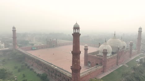 Vuelo-Aéreo-Hacia-El-Minarete-De-La-Mezquita-Badshahi-En-Lahore,-Pakistán,-Con-Aire-Brumoso
