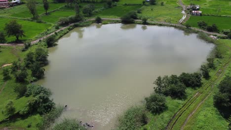 Malerische-Luftaufnahme-Von-Grünen-Feldern-Und-Ackerland-Im-Ländlichen-Maharashtra-In-Der-Nähe-Des-Teiches-Während-Des-Monsuns,-Indien