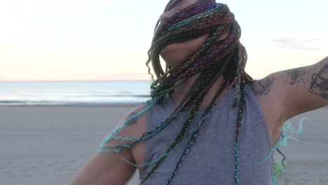 woman-with-colorful-braids-dancing-with-his-hair-moving-on-the-beach