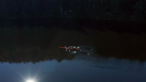 Tracking-shot-of-a-vintage-rowboat-revealing-3-people-on-a-lake-in-the-Black-Forest