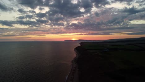 Aerial-4K-Drone-footage-of-High-Over-the-Isle-of-Wight-Coast-with-the-Sun-setting-on-the-Hills-in-the-Horizon-on-the-Isle-of-Wight-Coast