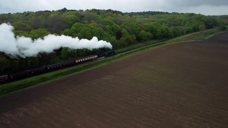 Aerial-Drone-4k-footage-of-a-Steam-Train-along-the-Poppy-Line-travelling-between-Holt-and-Cromer,-North-Norfolk