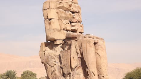 Ruinas-De-La-Estatua-Gigante-Del-Faraón-Con-Montañas-Al-Fondo-En-Los-Colosos-De-Memnon-En-Luxor,-Egipto.