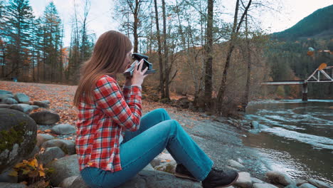 Photographer-woman-takes-Polaroid-photo-along-riverside-among-fall-colors