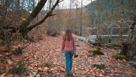 Photographer-woman-walks-along-riverside-among-fall-colors-and-takes-Polaroid