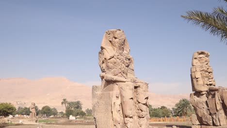Ruinen-Der-Beiden-Riesigen-Statuen-Des-Pharaos-Mit-Bergen-Im-Hintergrund-Bei-Den-Kolosse-Von-Memnon-In-Luxor,-Ägypten