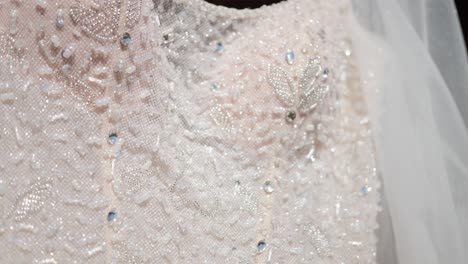 Close-up-luxury-design-details-of-embroidery-of-beads-and-crystals-on-the-white-satin-cloth-of-the-wedding-dress