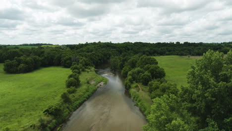 Aerial-View-Of-River-With-Shallow-And-Clear-Water-Amid-The-Green-Fields