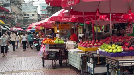 Fruit-vendors-selling-fresh-fruits-and-people-walking-in-Yaowarat-Chinatown,-Bangkok,-Thailand