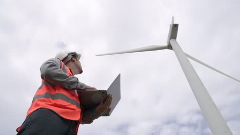 Progressive-engineer-working-with-the-wind-turbine,-with-the-sky-as-background.