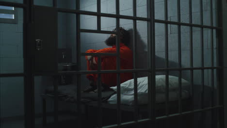 Schuldiger-Verbrecher-In-Orangefarbener-Uniform-Sitzt-Auf-Dem-Bett-In-Der-Gefängniszelle