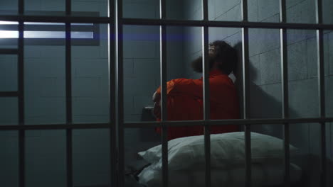 Gefangener-In-Orangefarbener-Uniform-Sitzt-Auf-Dem-Bett-Im-Gefängnis
