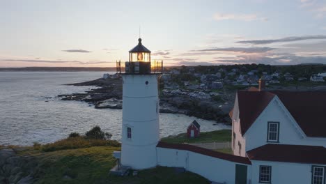 Aerial-Drone-shot-of-York-Beach-Maine-flying-over-Cape-Neddick-Nubble-Lighthouse-into-the-Sunset