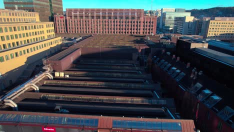 Aerial-drone-shot-over-Central-Train-Station-and-neighborhood-buildings-in-Oslo,-Norway-on-sunny-morning