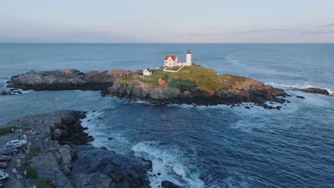 Aerial-Drone-shot-of-York-Beach-Maine-flying-towards-Cape-Neddick-Nubble-Lighthouse-at-Sunset
